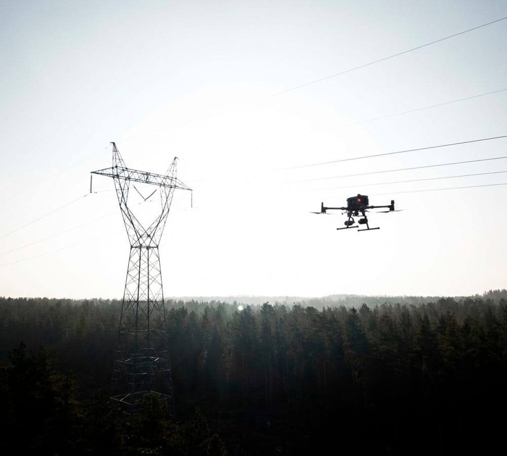 Cables de alta tensión difíciles de visualizar contra el cielo y vegetación durante una inspección con drone, ilustrando el problema de detección para la fotogrametría tradicional.